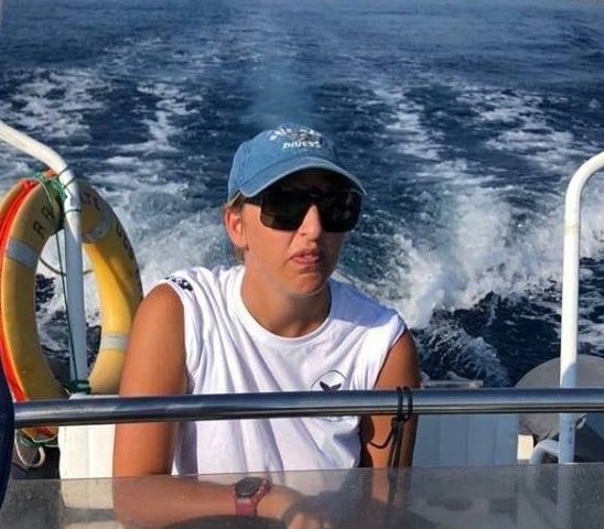 Woman in sunglasses and blue hat driving a boat